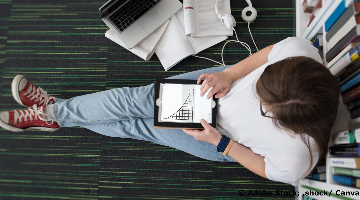 Junge Frau sitzt auf dem Boden einer Bibliothek und arbeitet mit einem Tablet, auf dem eine sinkende Exponentialfunktion zu sehen ist.