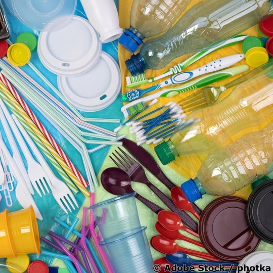 Draufsicht auf bunt gemischtes Einwegplastik des täglichen Gebrauchs wie Flaschen, Becher, Besteck und Trinkhalme