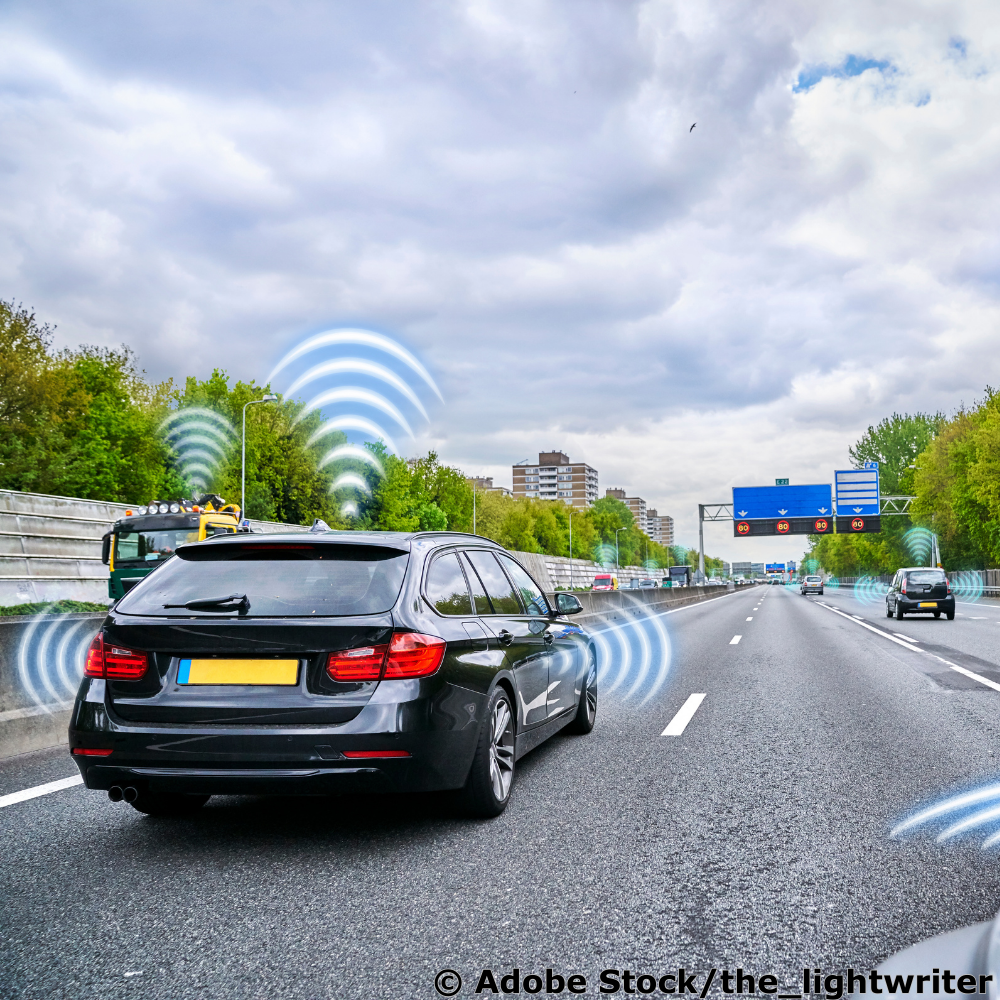 Schwarzes Auto auf einer Autobahn mit grafisch angedeuteten Sensoren. 
